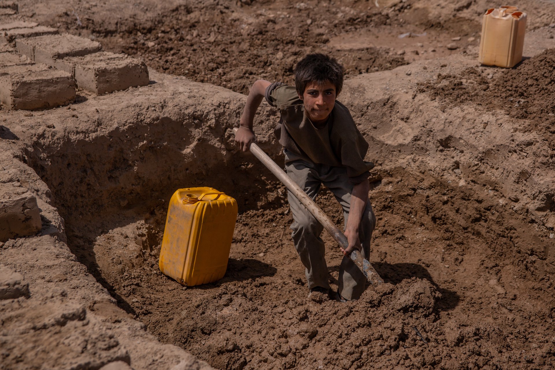 A young person shovels mud for a structure