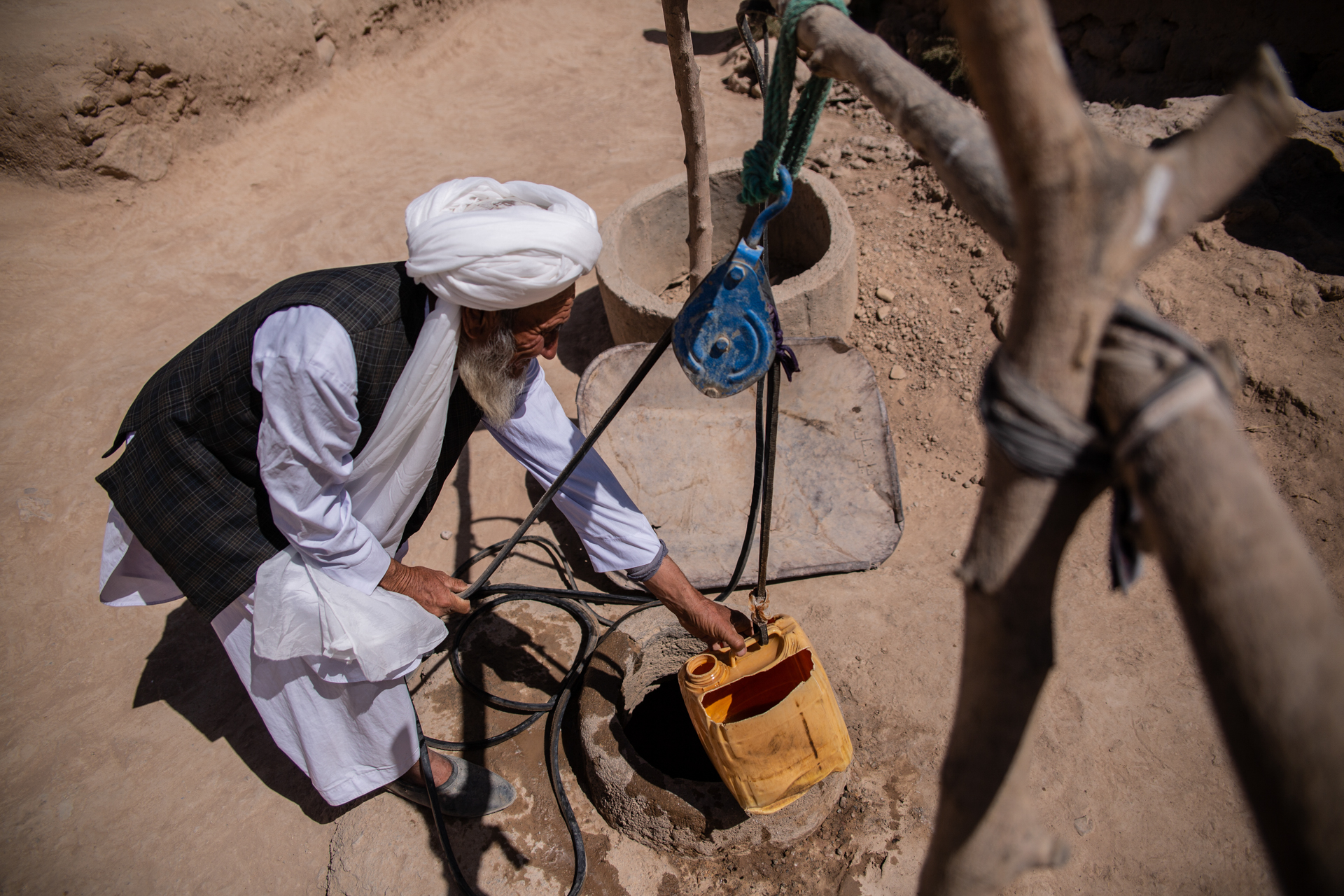 An older man in Afghanistan draws water from a well