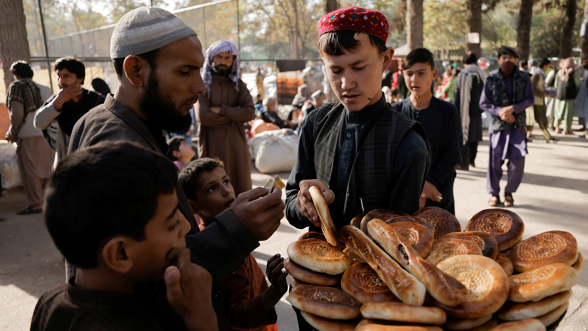 A boy sells bread at a makeshift shelter for displaced Afghan families, who are fleeing the violence in their provinces, at Shahr-e Naw park, in Kabul, Afghanistan, 4 October 2021. 