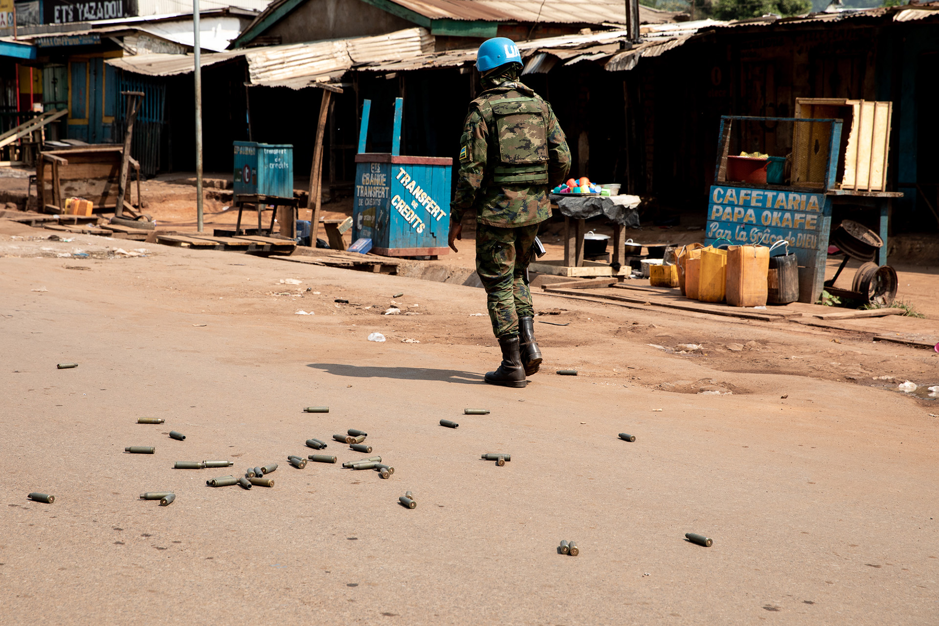 A soldier is pictured walking away from the camera, with empty bullet casings scattered on the street.