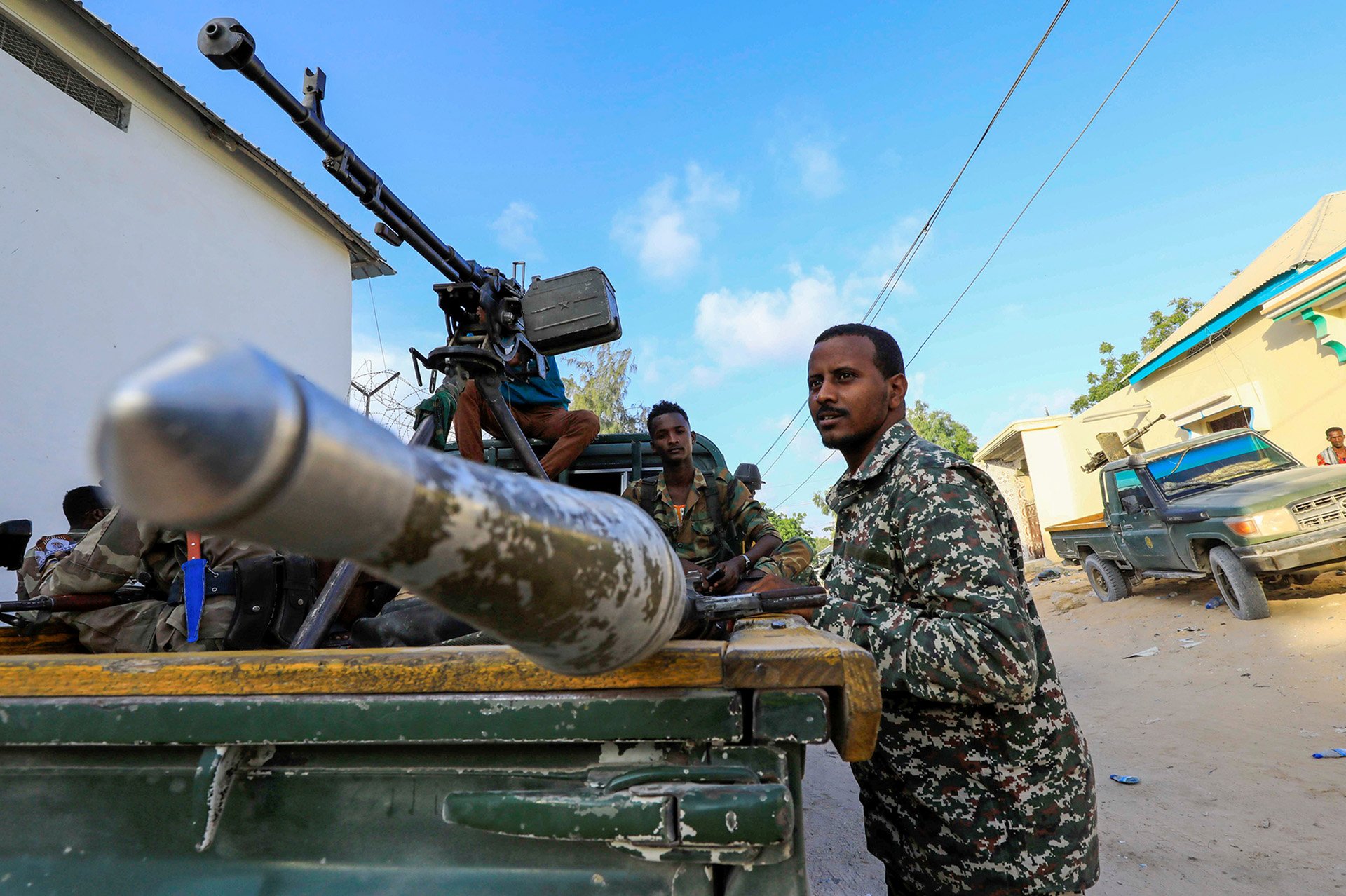 Opposition forces muster in the Black Sea area of Mogadishu’s Hodan district, 17 April 2021. A man dressed in fatigues stands beside an army tank, looking past the camera.