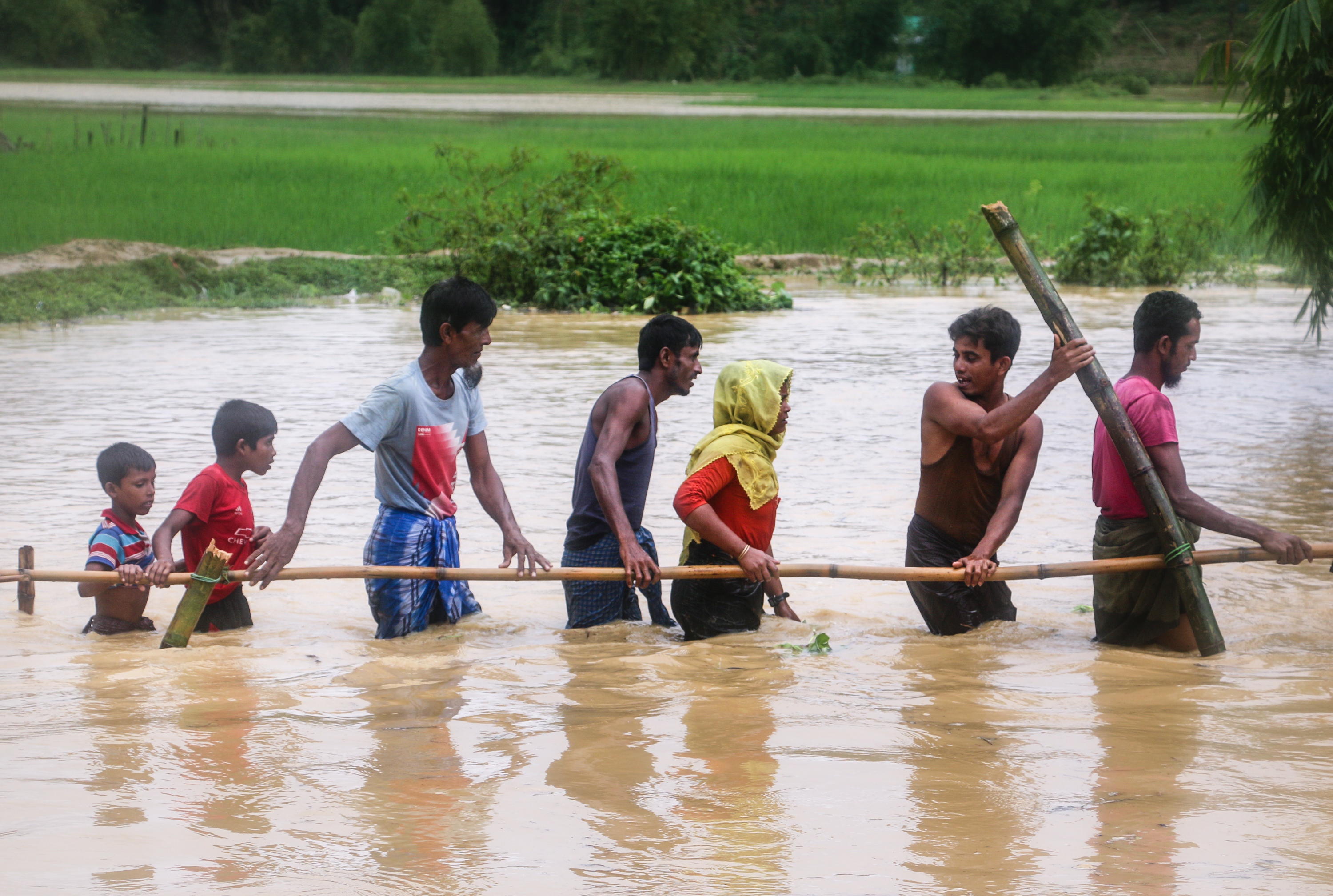 Refugees walk across a flooded field