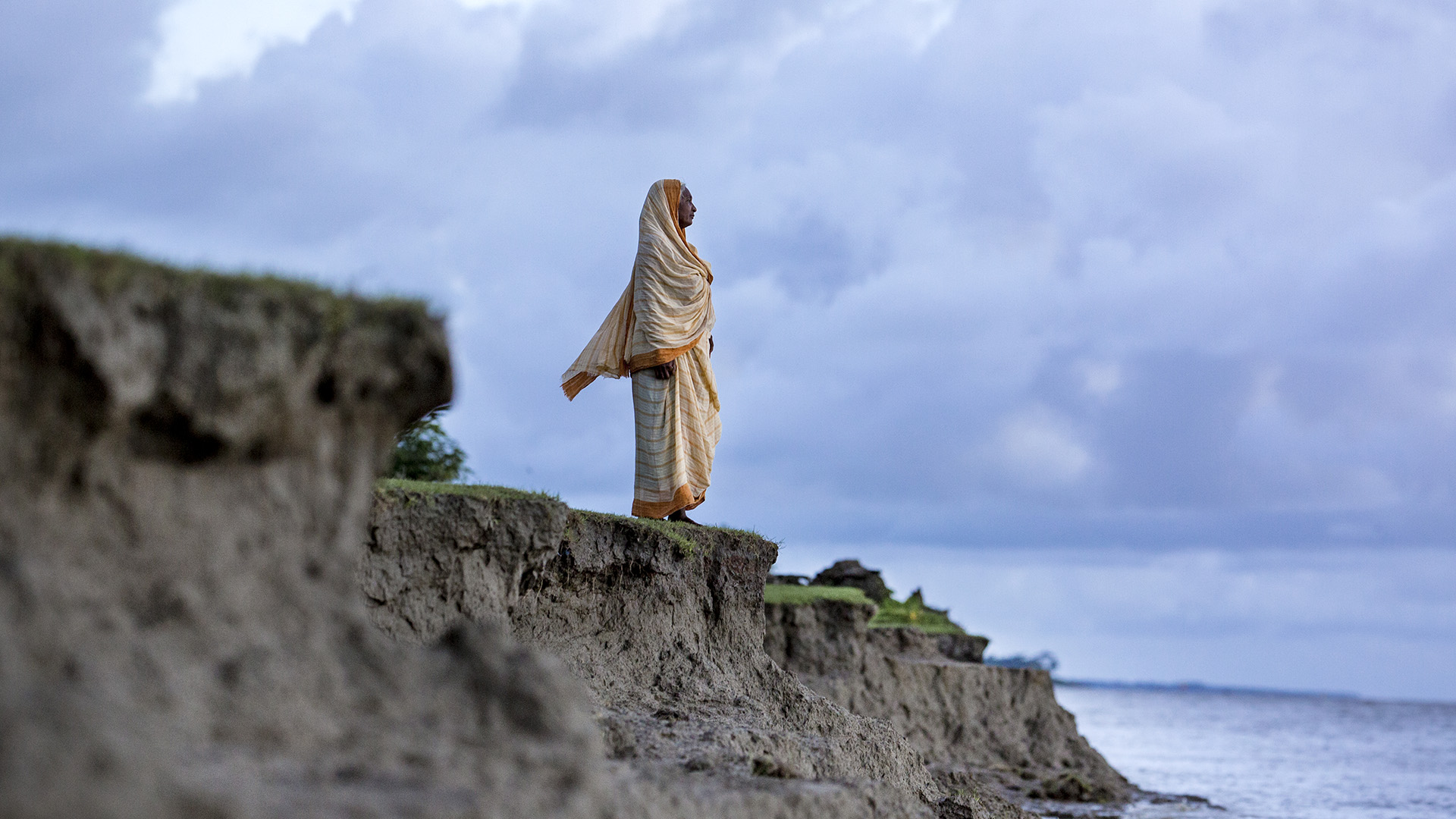 Tulu Rani, 72, stands near the site of her former home, which eroded into the sea, on Manpura Island, where Bangladesh’s Meghna River empties into the Bay of Bengal. Erosion occurs naturally in Bangladesh, but climate change is worsening the problem.