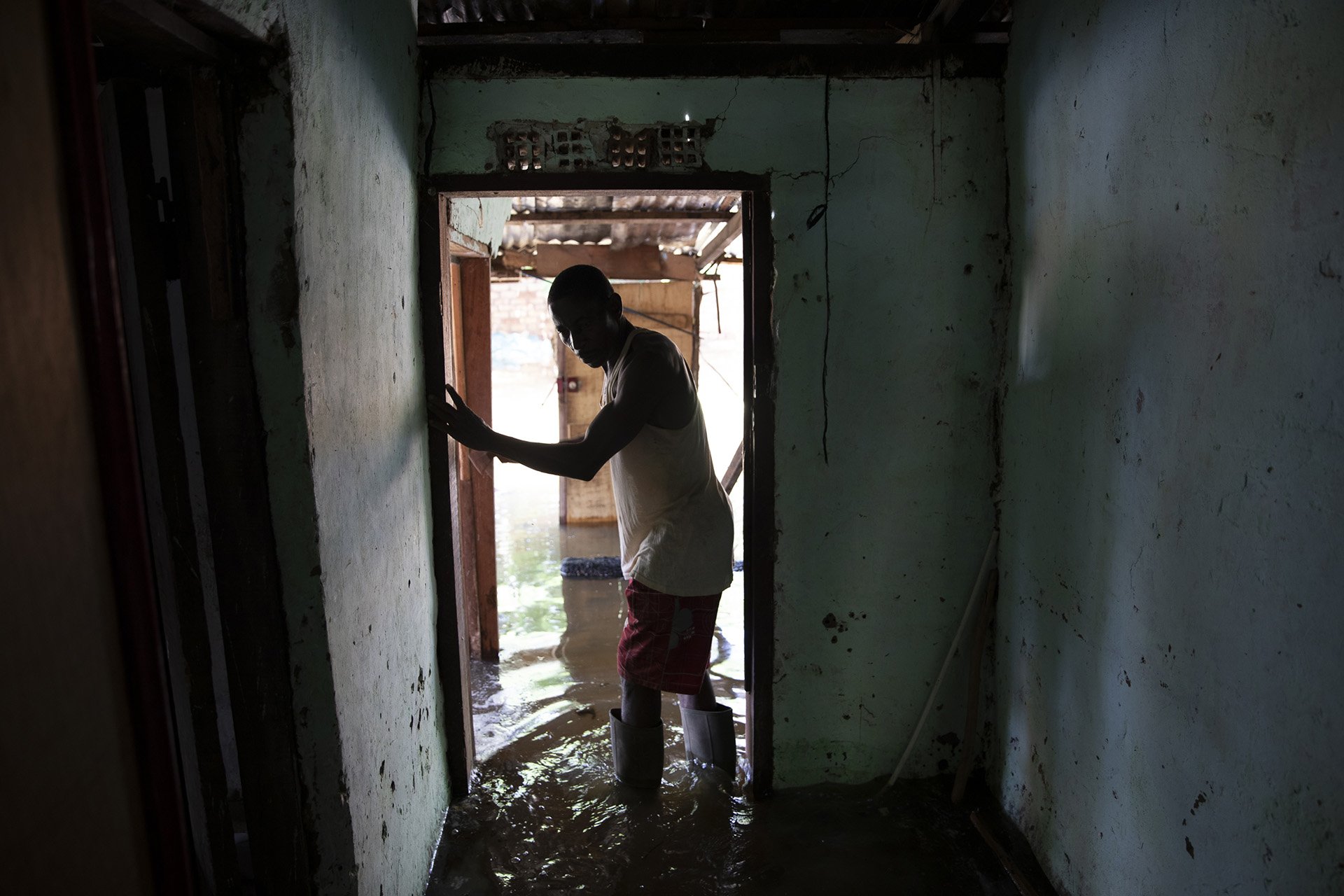 Since his house was flooded, Stanislas Begia, 40, sleeps outside with his wife and eight children. Meters away from his home, a path of ground is left dry. 