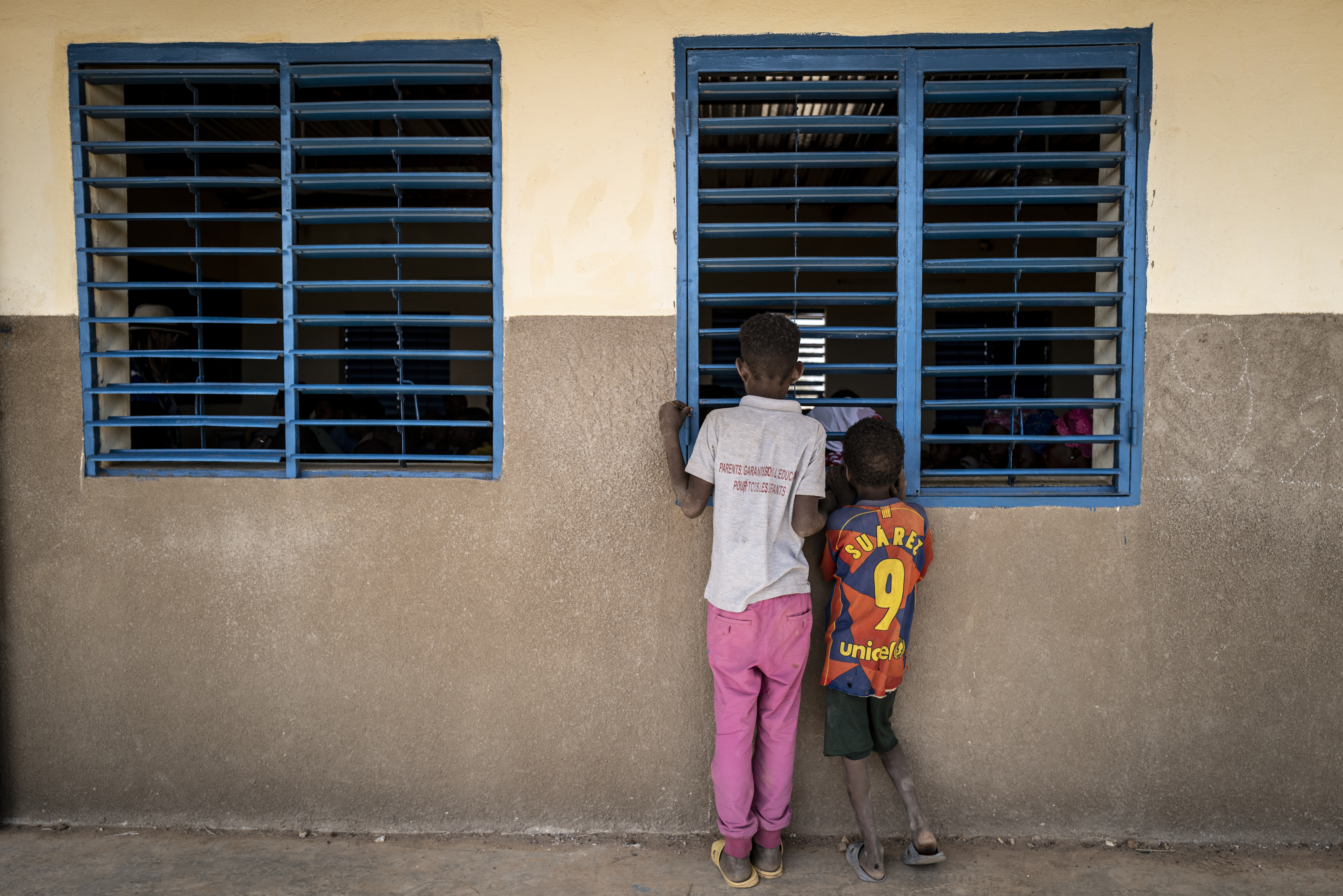 Young Malian refugee children peak into a school in Goudoubo camp