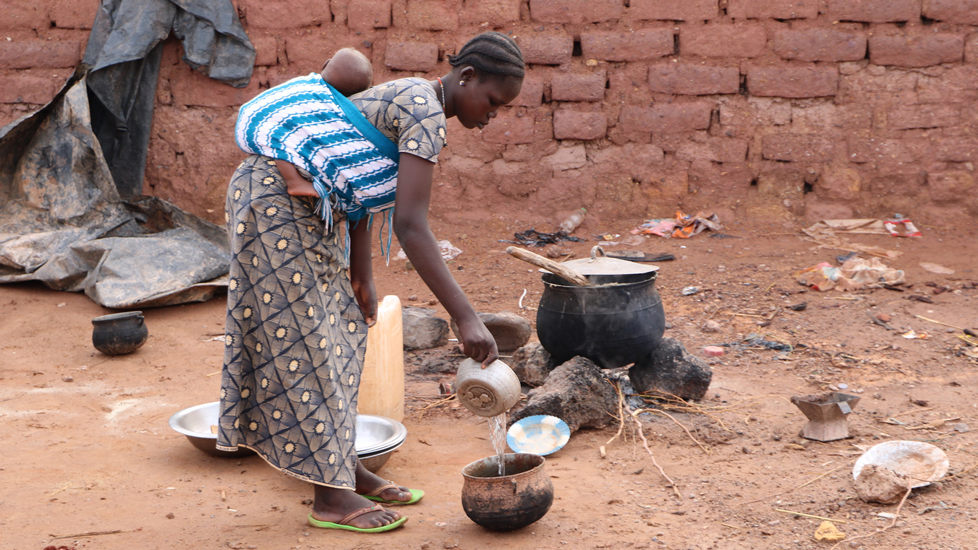 A woman cooks for a family of displaced people in Kongoussi