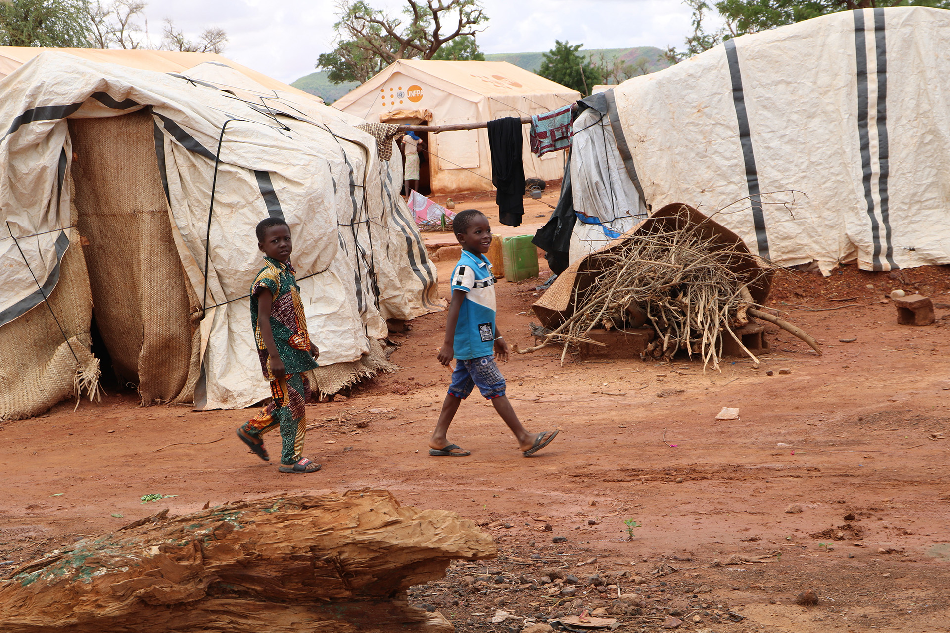 Children walk through a displacement camp in Kongoussi