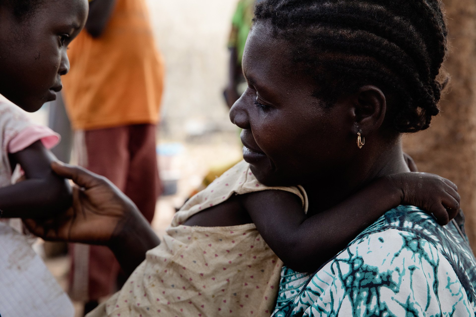 The profile of a woman as she holds her daughter. 