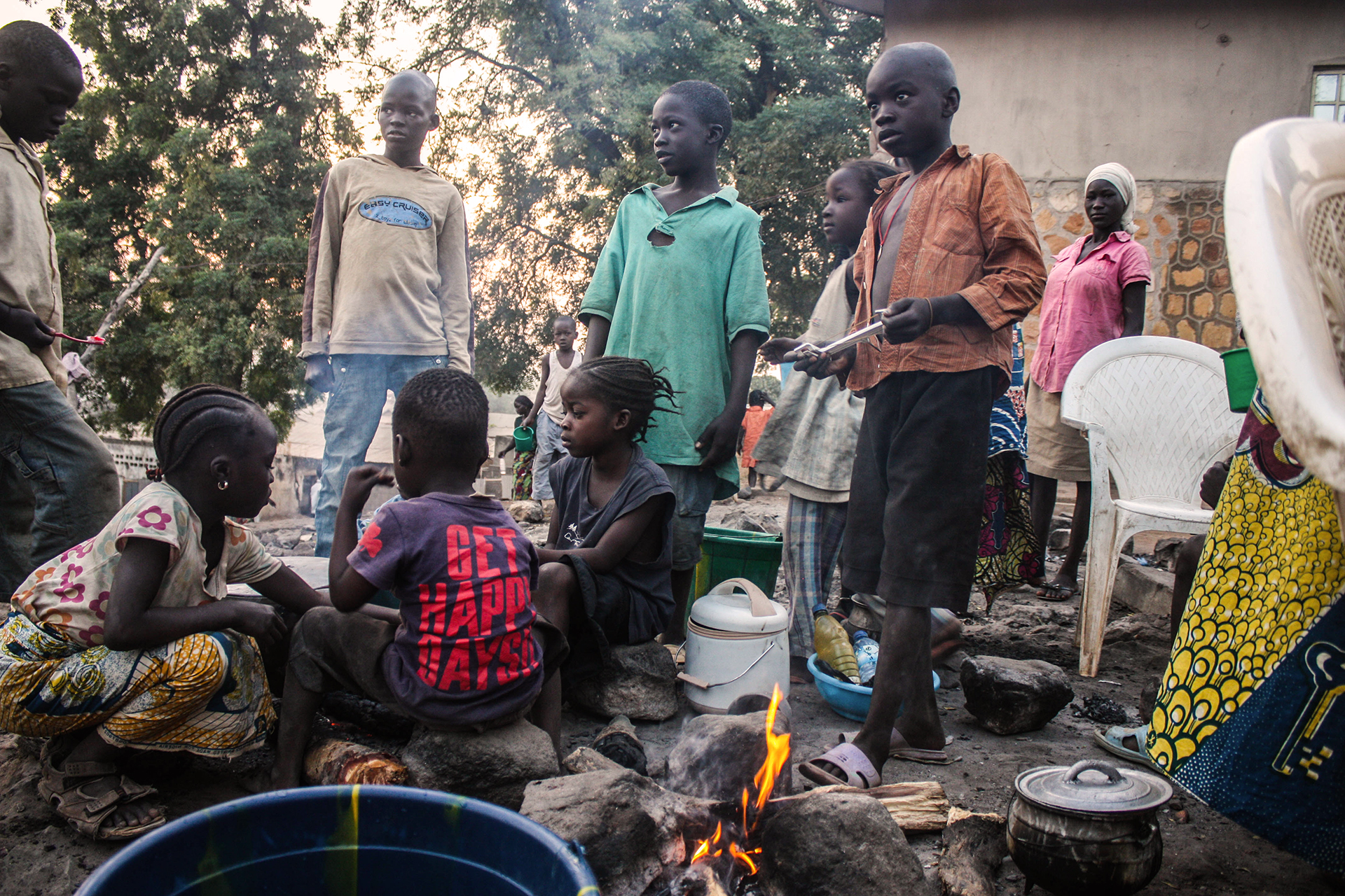 Children in a displaced person camp around a cooking fire