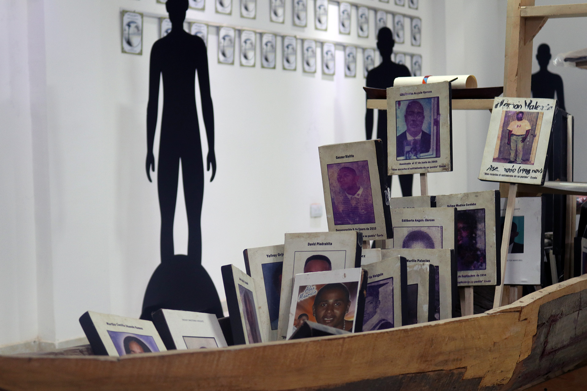 Photos of victims of violence are propped up on stakes in a wooden boat