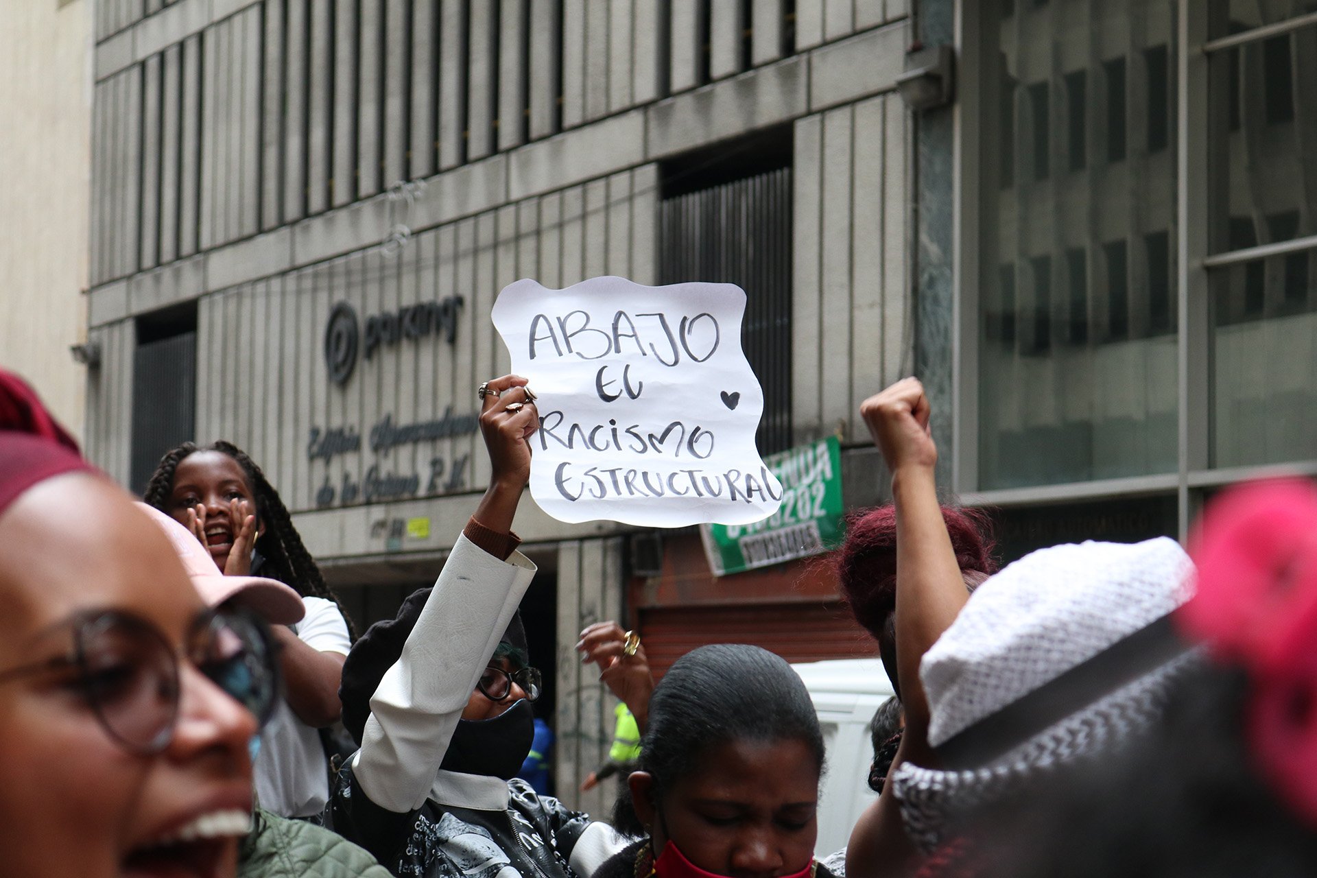 A girl holds a sign above her head at a protest on a street in Bogotá