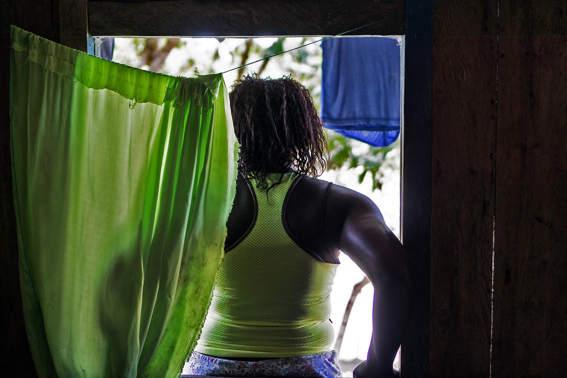 A woman stands in a doorway with her back to the camera. 