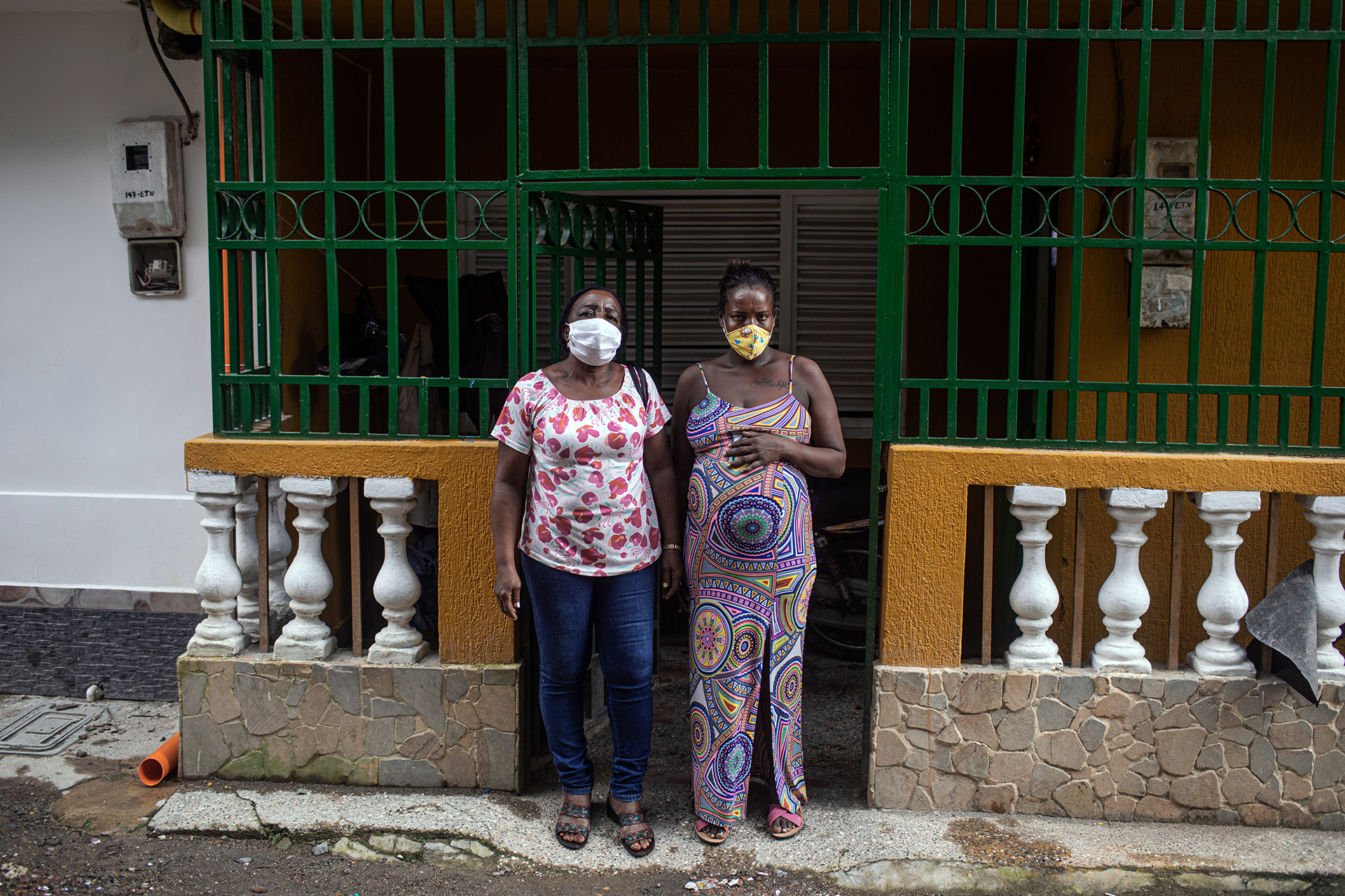 A pregnant mother and Luz Maritza Moreno, a traditional midwife, stand outside of a home in Quibdó, Colombia.