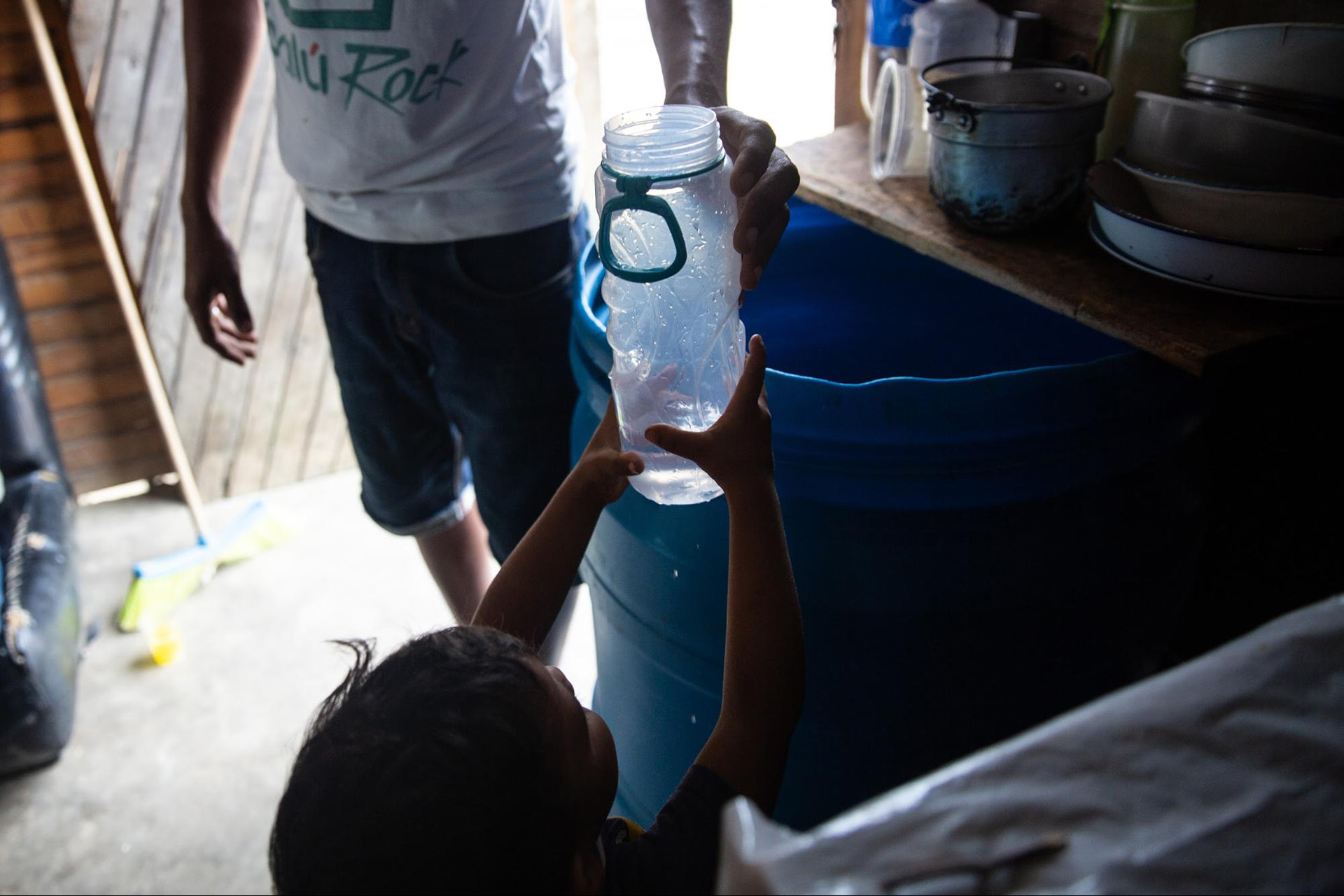 Elisabet Gomez’s son, Fabian, takes a bottle of water from a barrel