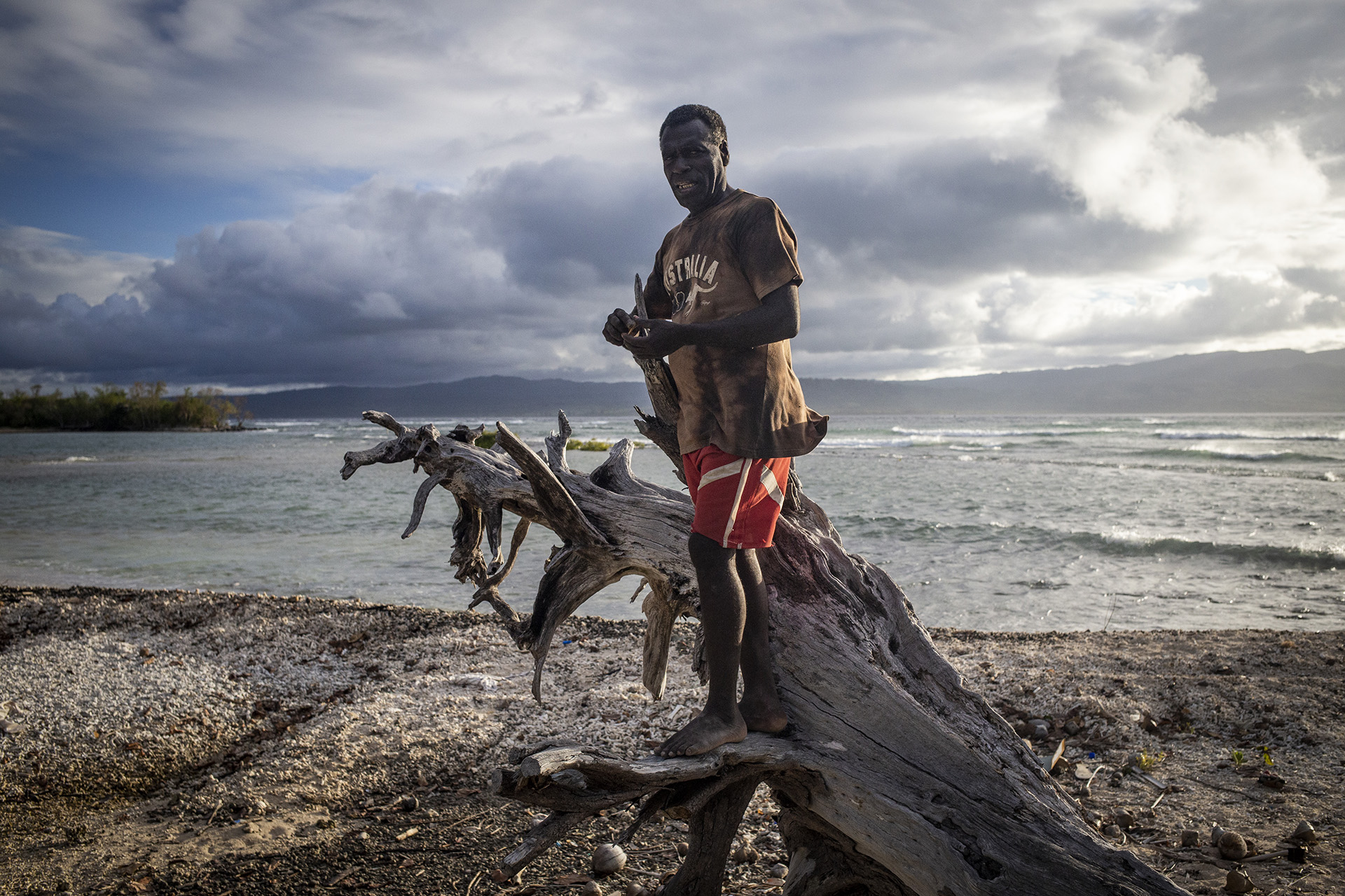 A photo of Jeffrey Daniels, 45, standing on a piece of driftwood by the sea