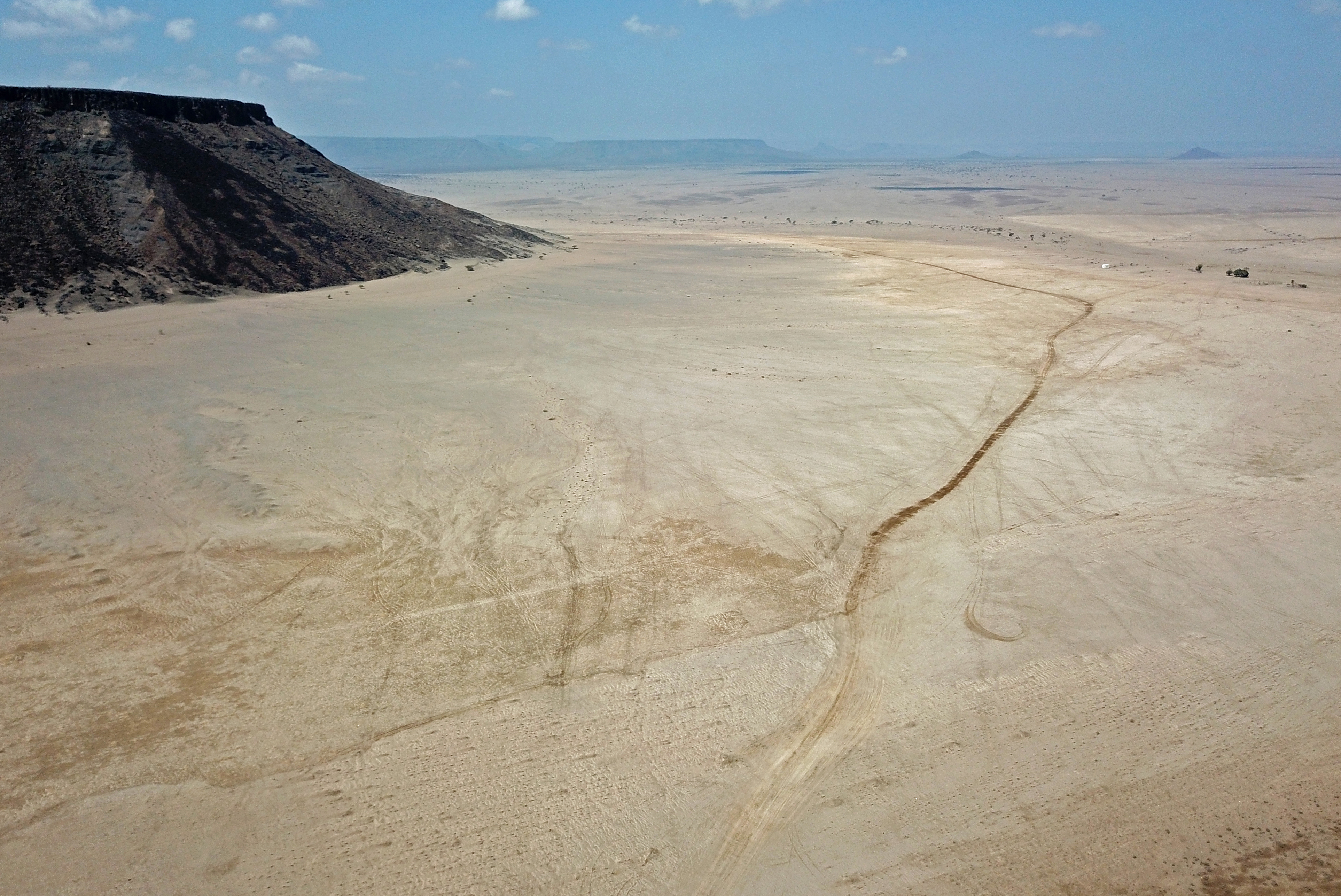 An aerial view of a desert road with little in the distance