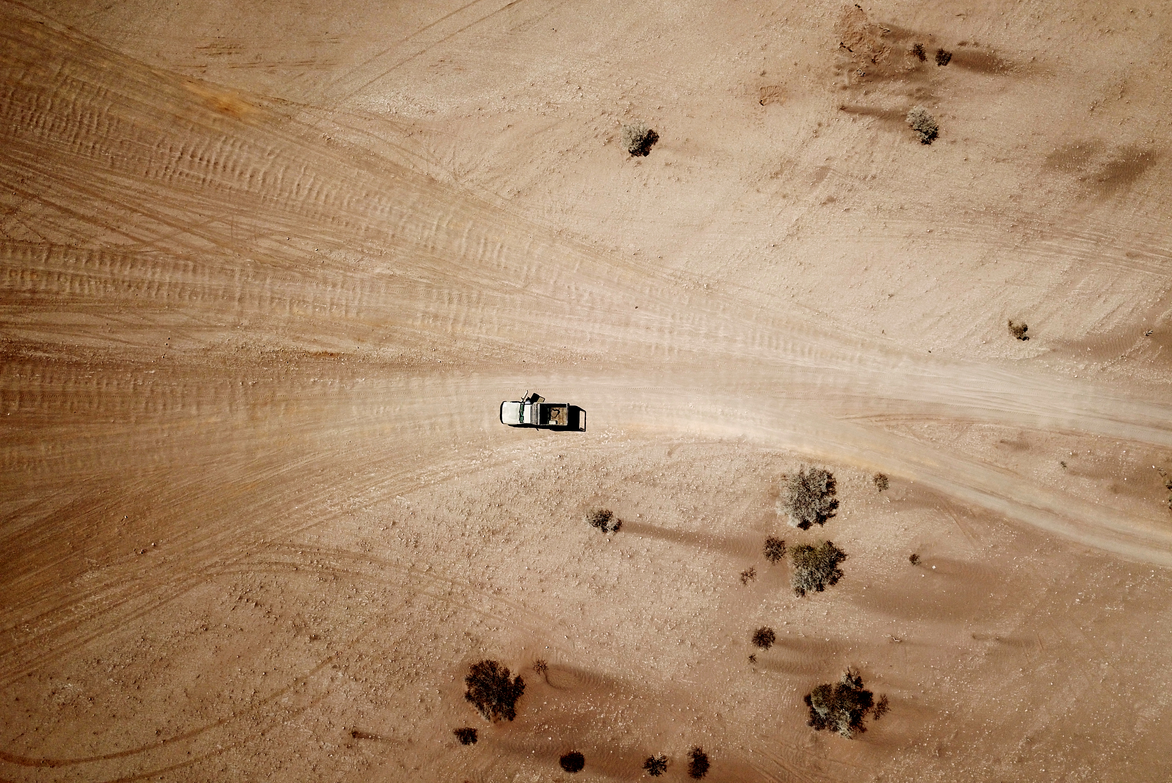 An aerial view straight down onto a truck in the desert