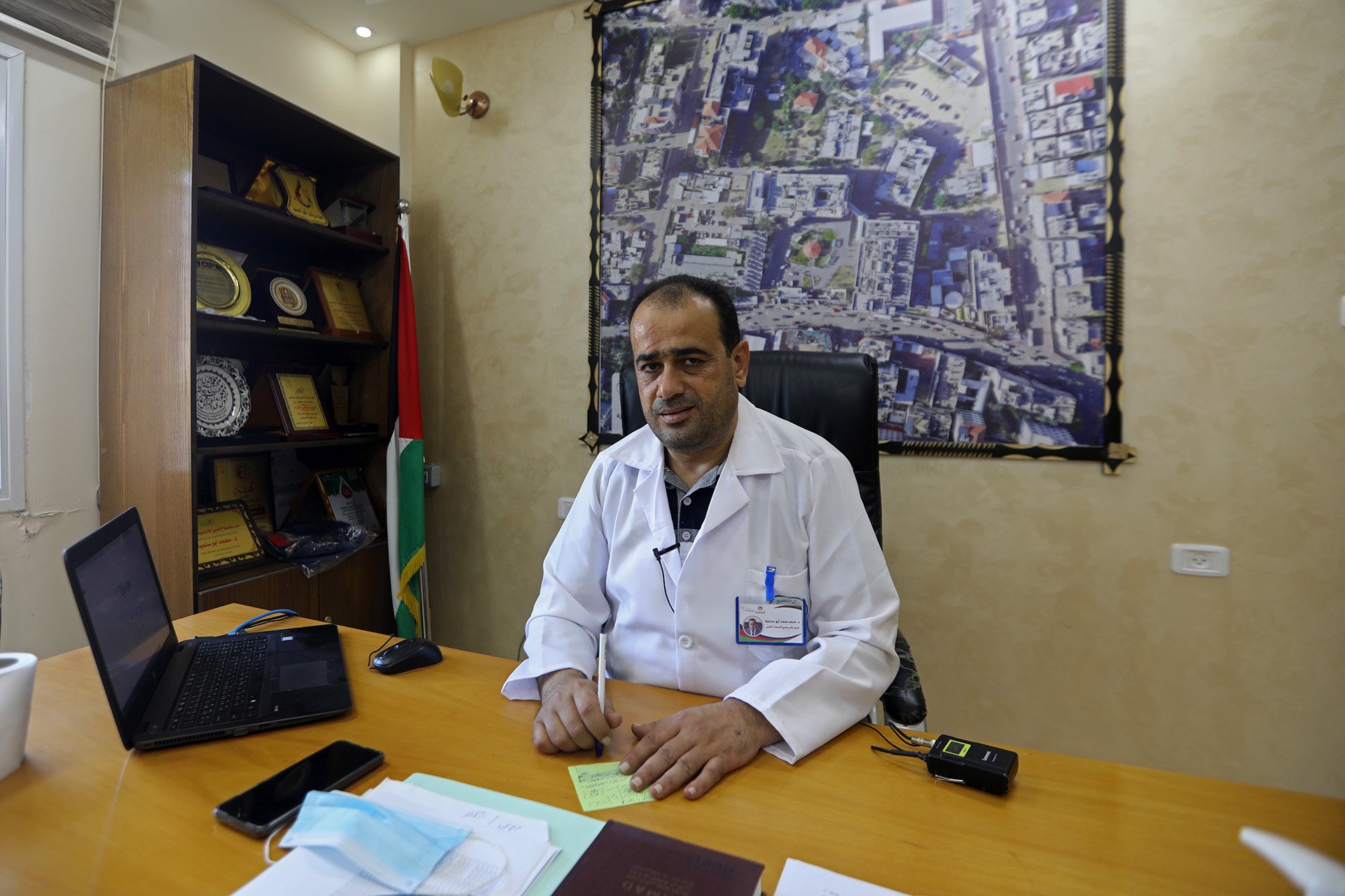 A doctor sits behind a desk in his office. 