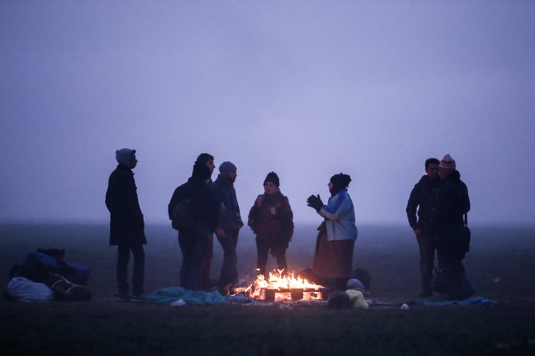 A Syrian family warming themselves at a fire camp