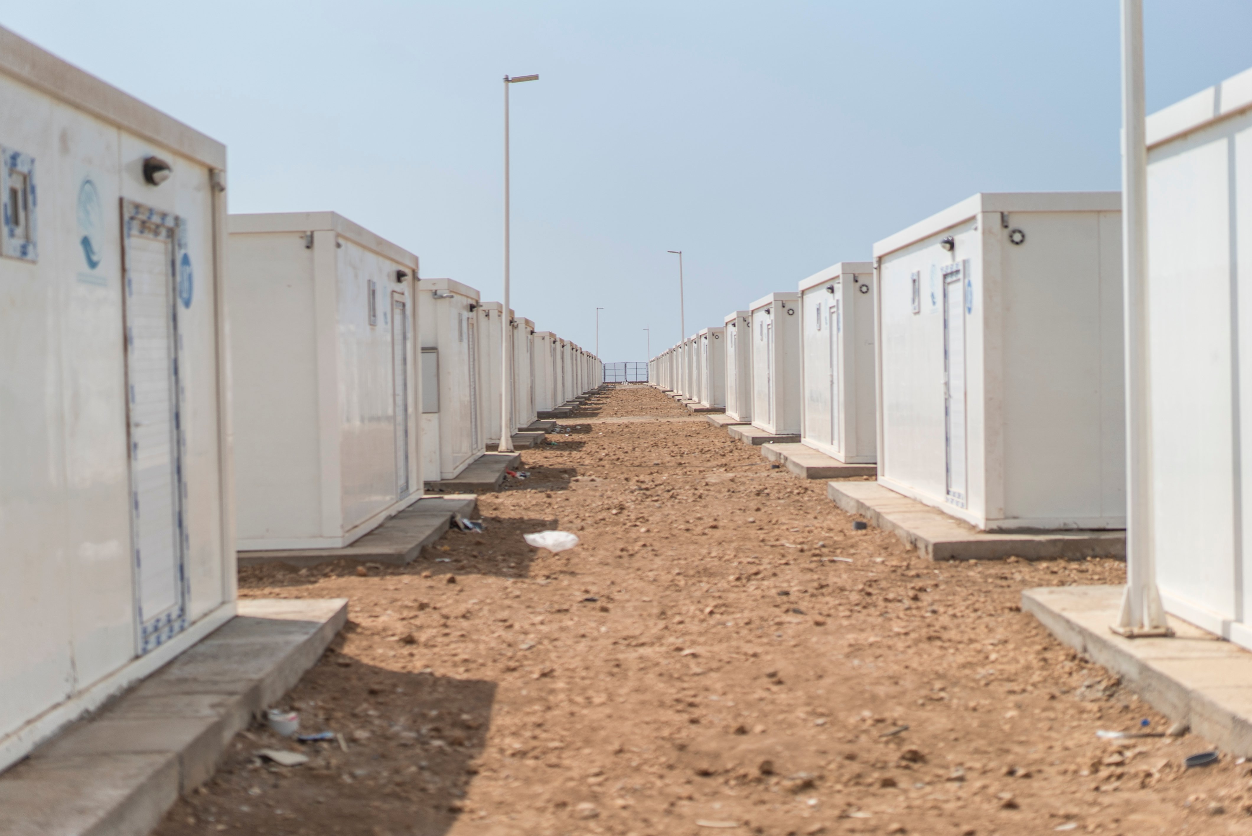 A view between two long rows of identical white box shelters