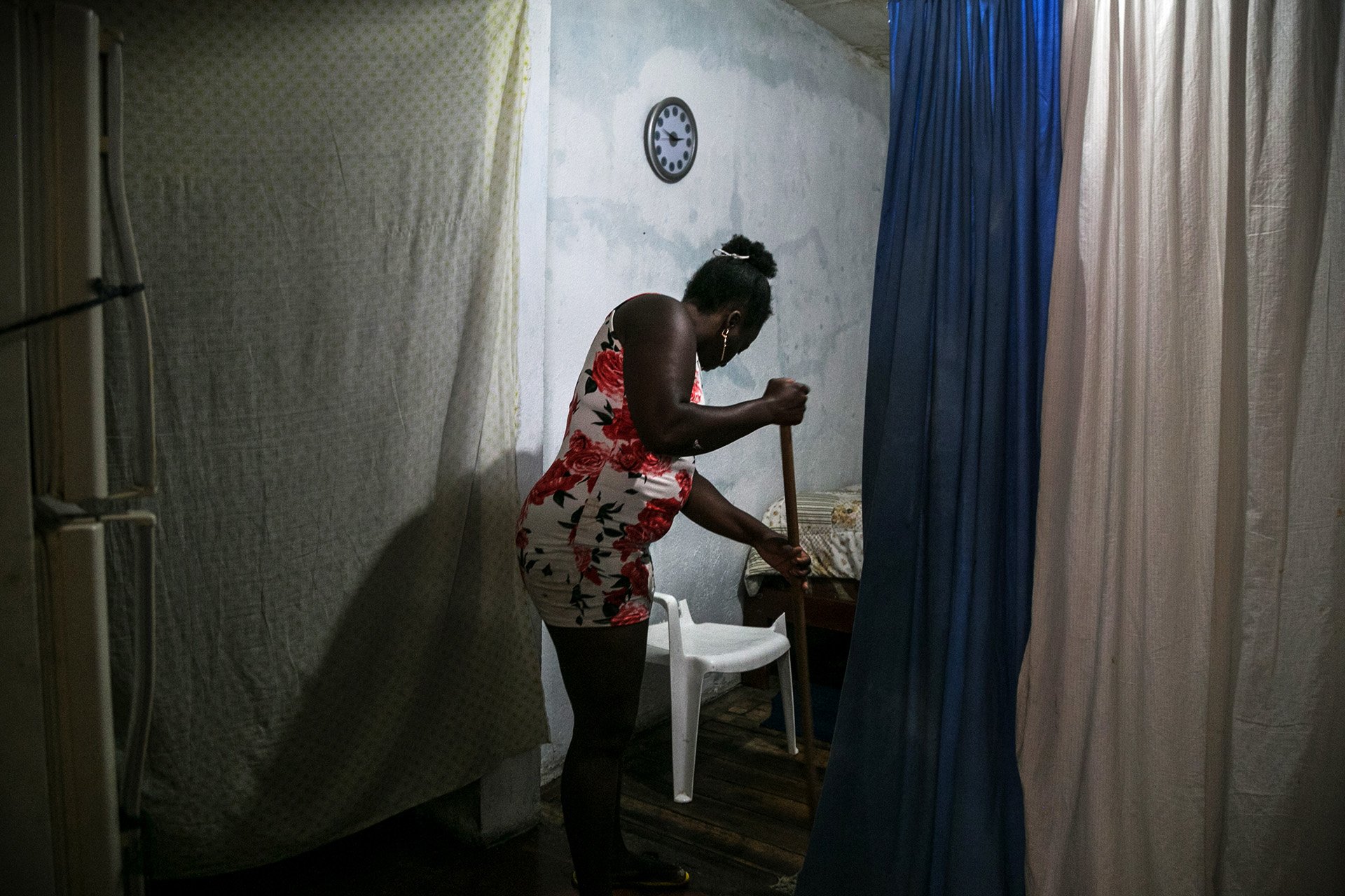 A photo of Claudia in her apartment, with her back to the camera. Refugees in Ecuador can often only afford to live in neighbourhoods where organized crime is prevalent and where houses are in a state of disrepair.