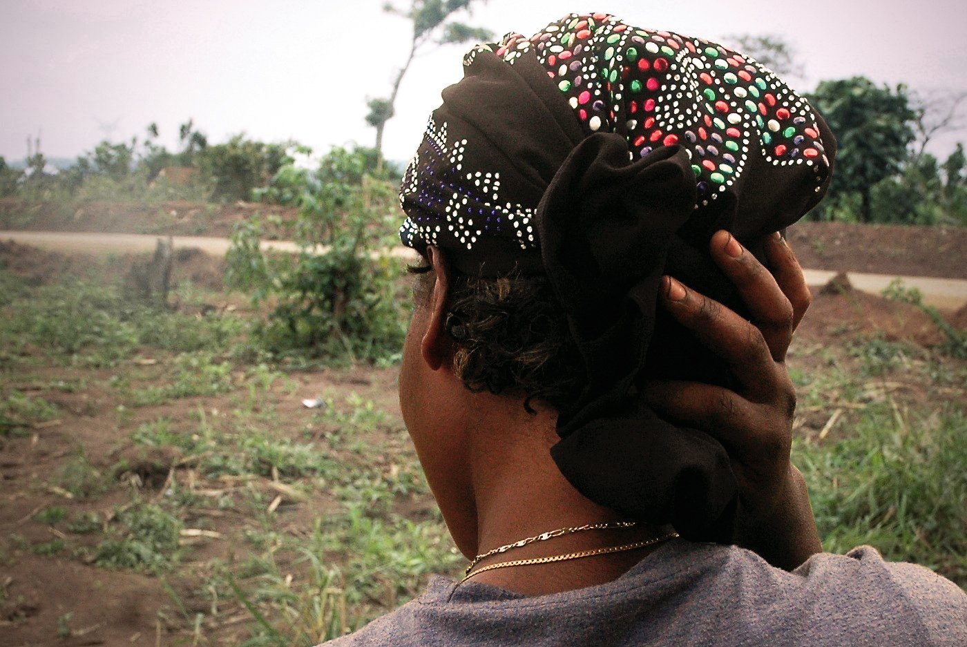 A portrait from behind of a Congolese rape survivor in a green field