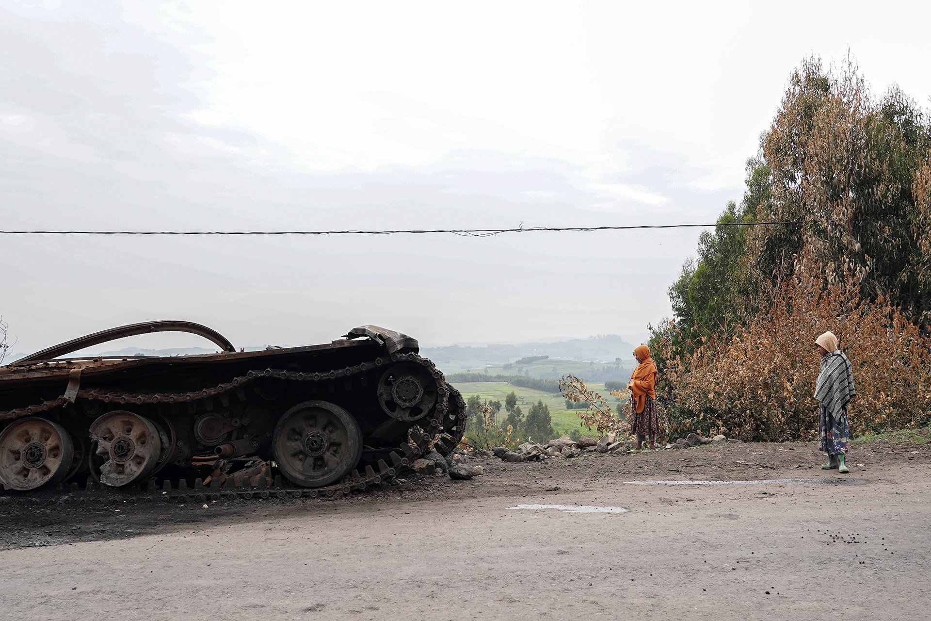 Residents walk past an abandoned tank on a main road in Amhara region. Fighting has intensified in recent days after the government launched a fresh anti-rebel offensive. 