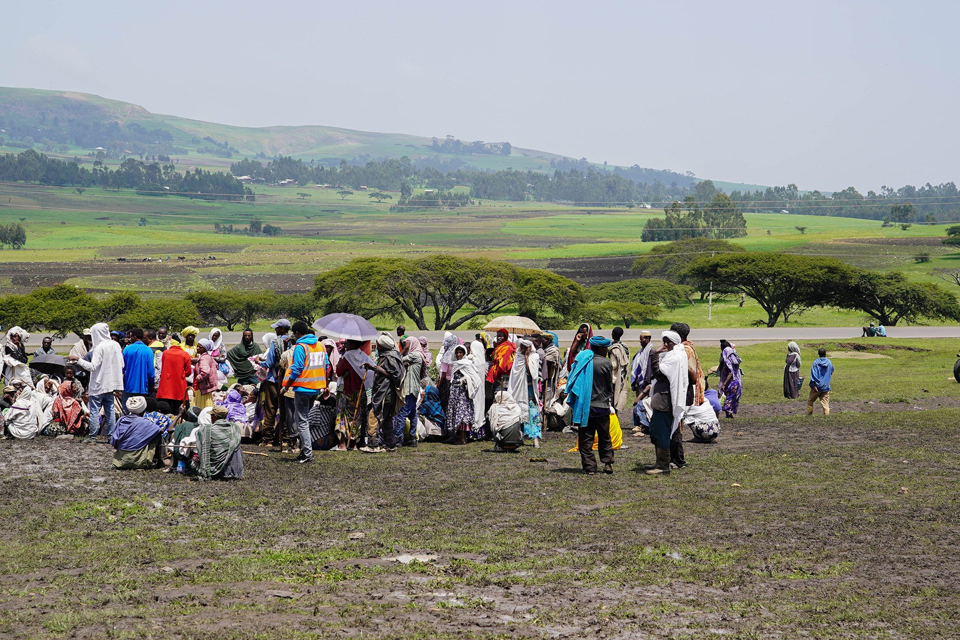 A group of internally displaced people wait on an arid landscape to receive aid in the town of Dabat.  