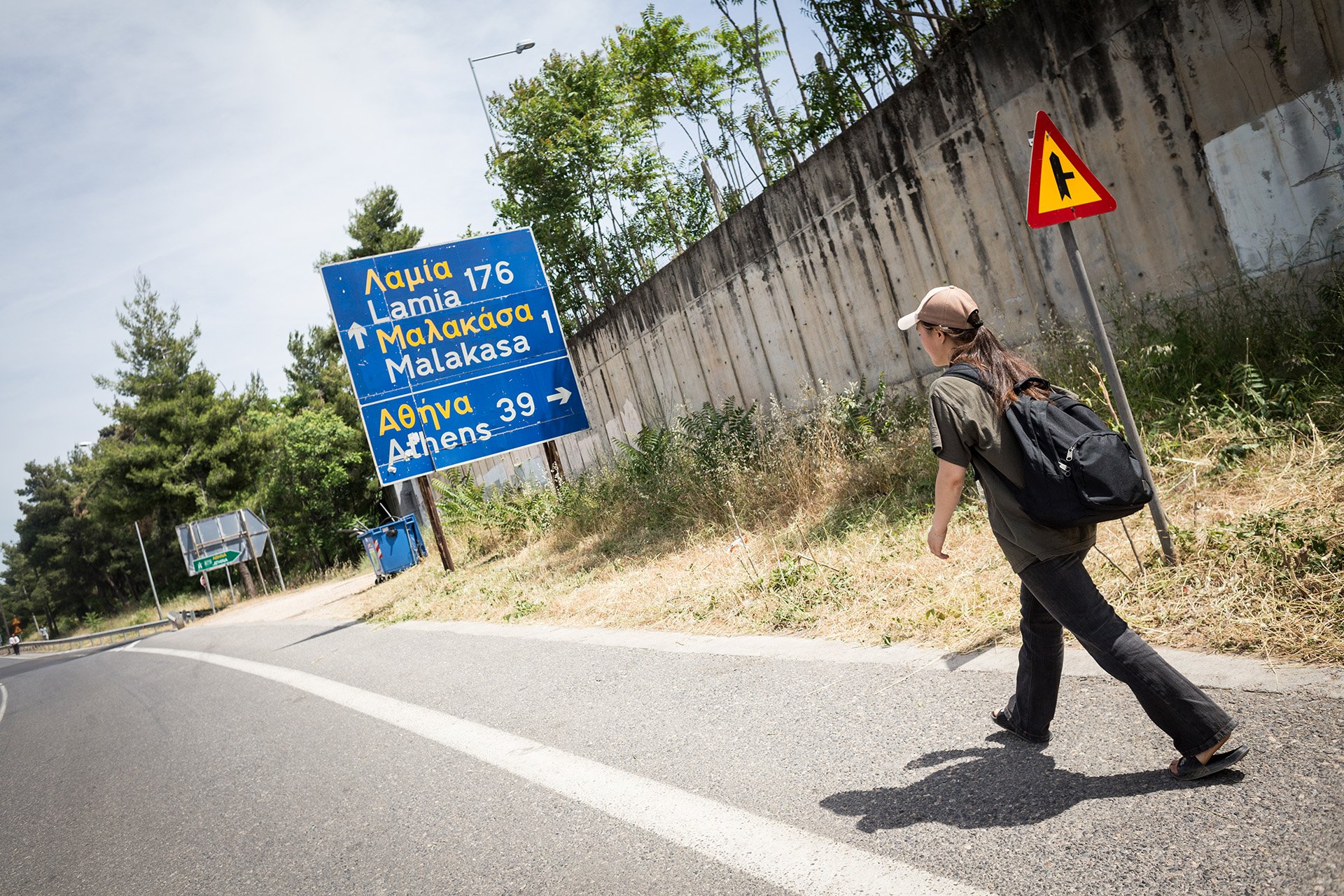 Sohalia, a communication coordinator with Yoga and Sport, walks on the road adjacent to the Malakasa refugee camp, where her mother and sister live, in June 2021. The isolated camp is 40 kilometres from Athens, an hour’s train ride away. 