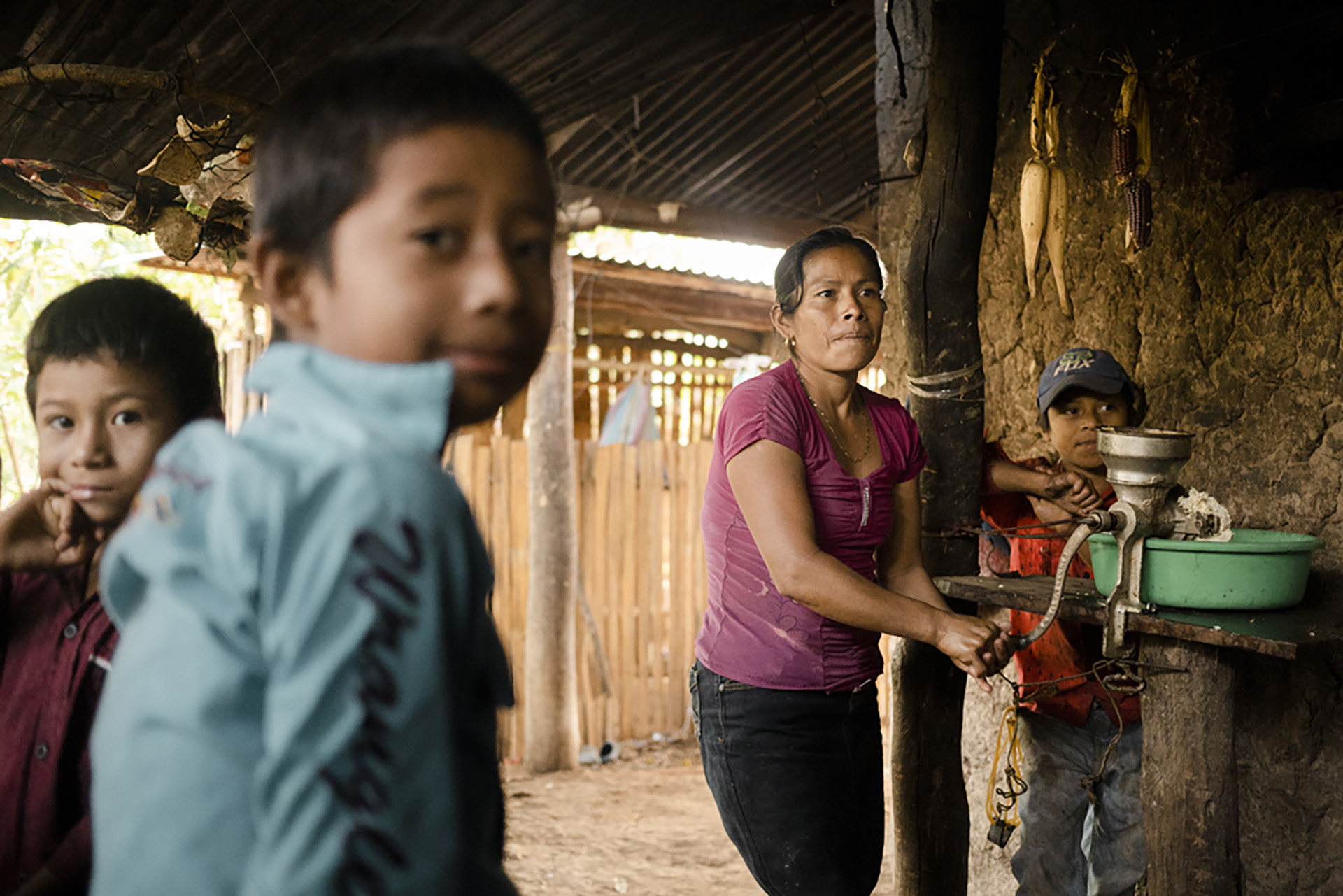 García Pérez uses a mincer to grind cooked maize. Before she bakes the tortillas on an open fire, she grinds the dough again on a stone. The children are waiting for breakfast.