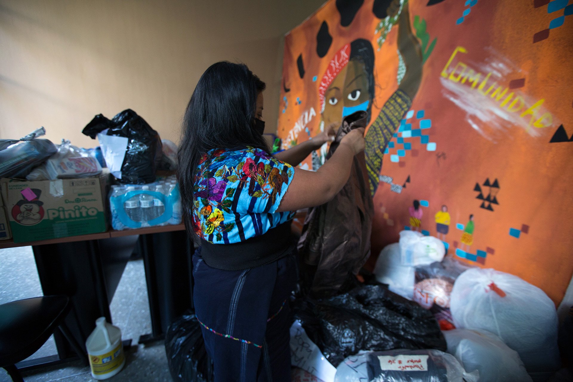 A member of the Tz'ununija' Indigenous Women's Movement sorts through clothing donations for people affected by Eta dropped off at the group's office in Guatemala City 