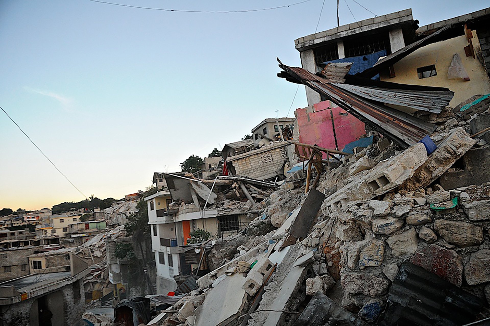 A photo shows a close-up image of a hillside of damaged buildings.