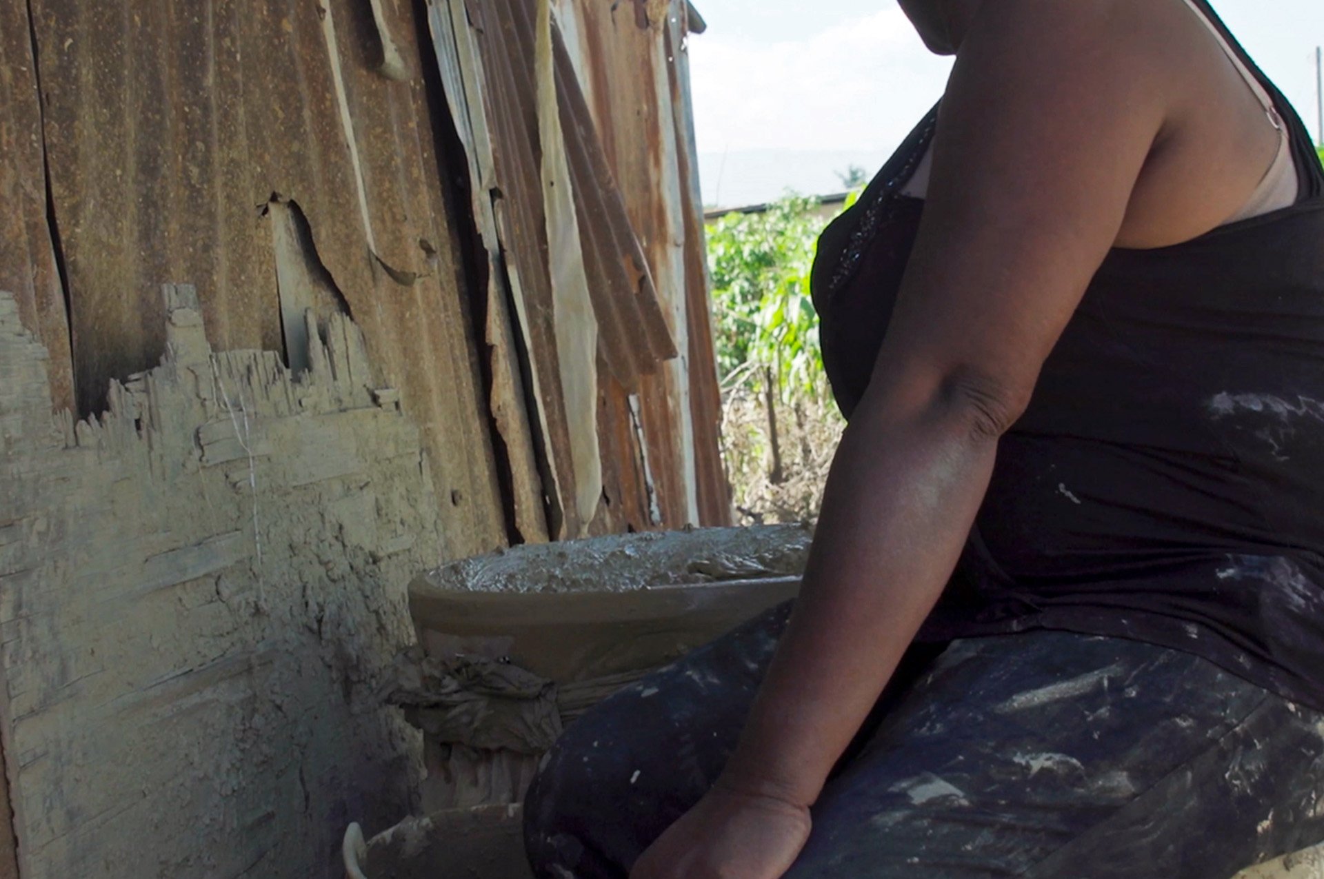 A woman prepares a mud cake made of dirt, salt, vegetable shortening, and water. The cakes are used in traditional healing and to stave off hunger.