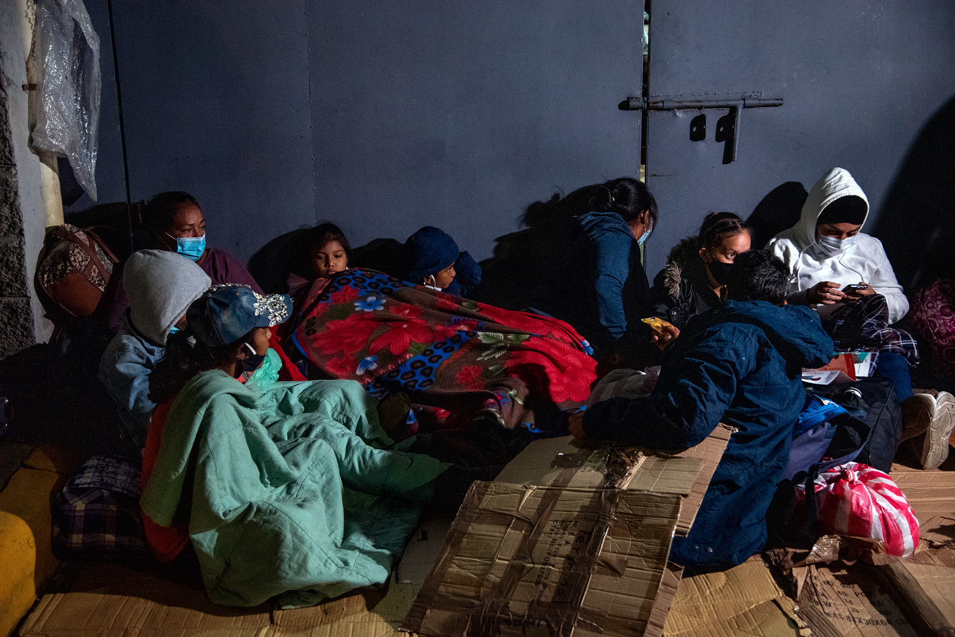 A family of Hondurans huddles together to keep warm in San Pedro Sula as they wait for the caravan to start.