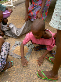 [Liberia] Child sweeping up spilt grain from UNHCR food truck in Monrovia.
