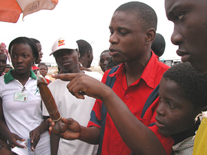 [Angola] A youth activist demonstrates condom use in a marketplace in Viana.