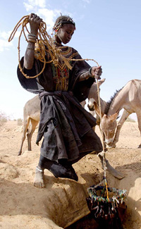 [Niger] A young Nigerien slave collects water from a traditional well in far west Niger. Water is scarce in the desert region of Tillaberi and these traditional wells only touch the surface level of the water bed.