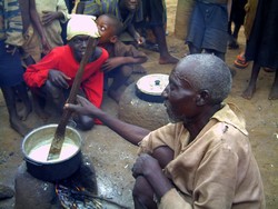 [Burundi] And old Burundian refugee man cooks maizemeal on a clay stove at the Nyakimonomono way station in Kibondo District, northwestern Tanzania. [Date picture taken: March 2006]