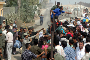 [Gaza] A crowd of Palestinians throw stones at Palestinian security forces preventing them from passing the border point at Raffah, between Egypt and Gaza Strip, 17 September 2005. Gaza has no sea port and Israel has not agreed to allow its international 