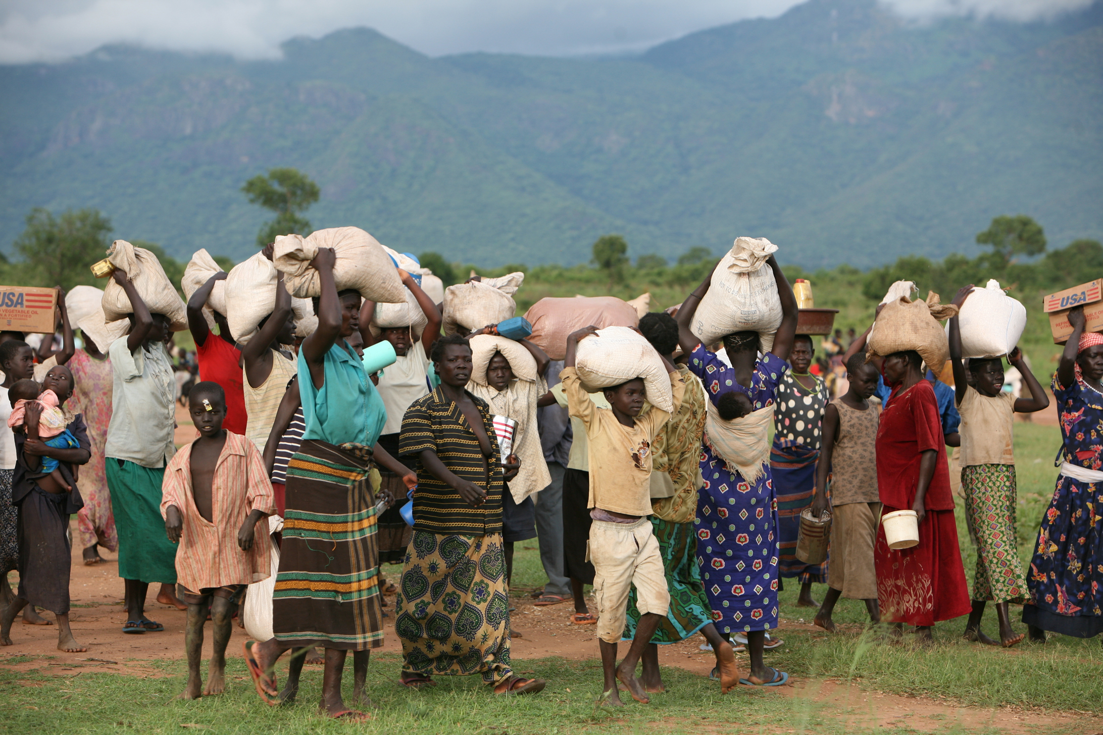 Families carrying home their share of food, Oromi IDP camp, Kitgum District, northern Uganda, 18 May 2007. WFP gives IDPs partial rations to supplement what they can grow near the camps.