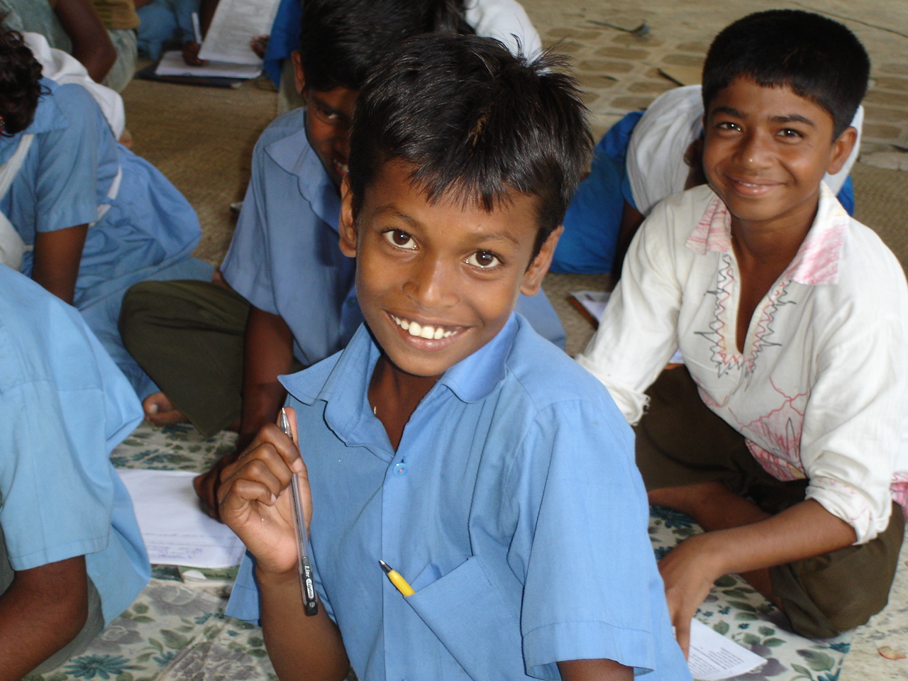 A young primary school student outside Dhaka smiles to the camera.