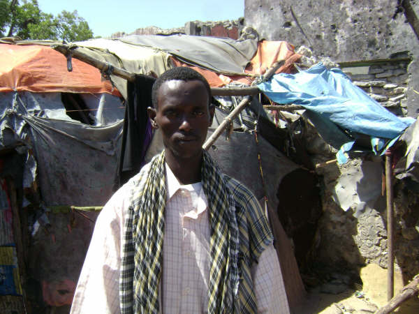 Madeey Suufi, standing in front of what is left of his home where his family was killed when a shell hit. [2 Jan 2008]
