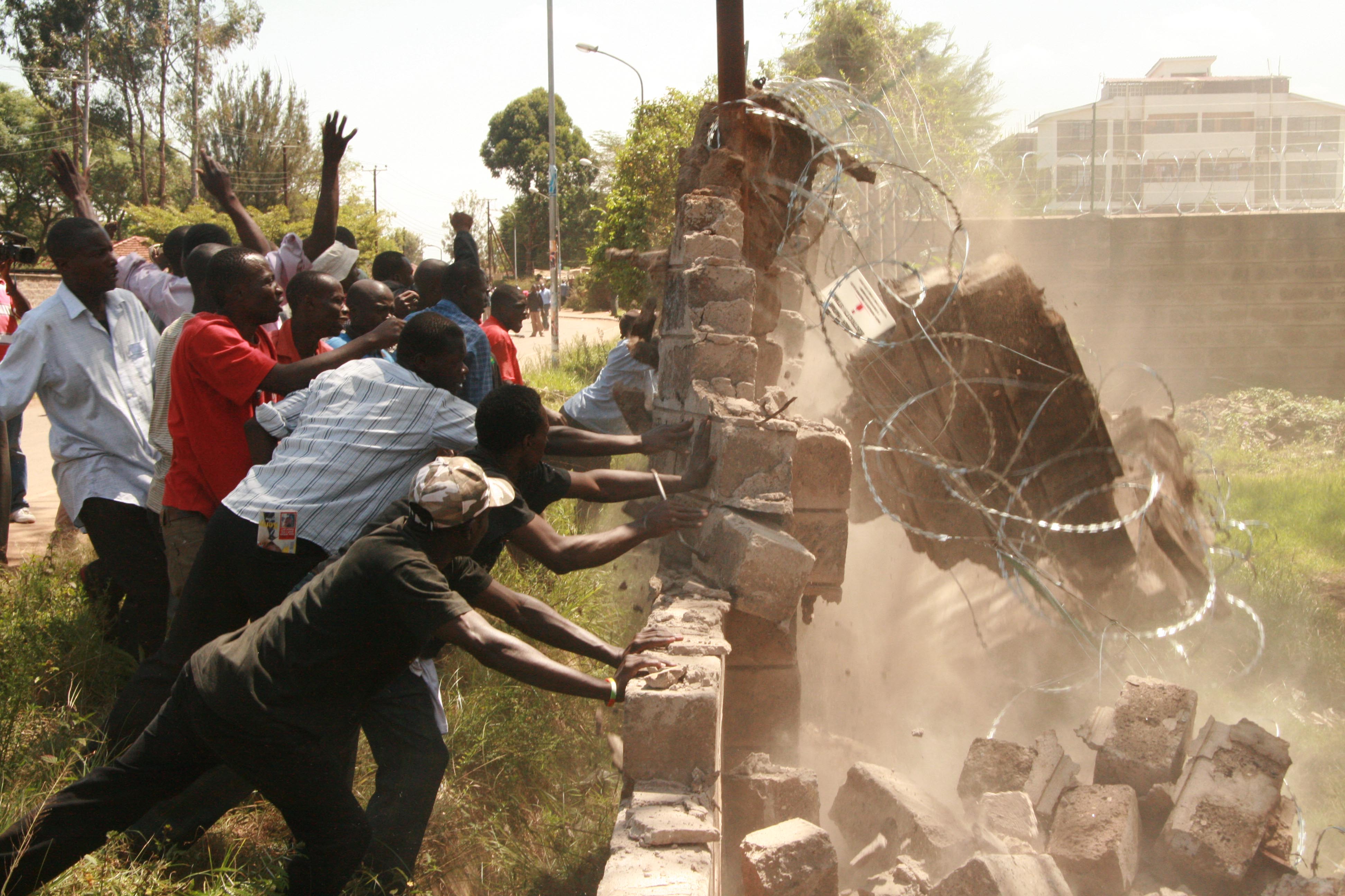 Irate youth demolish the wall of Telkom Kenya after a funeral service that was organised by the opposition ODM, Nairobi, Kenya, January 2008. The crowd was later dispersed by police through  the use of tear-gas.