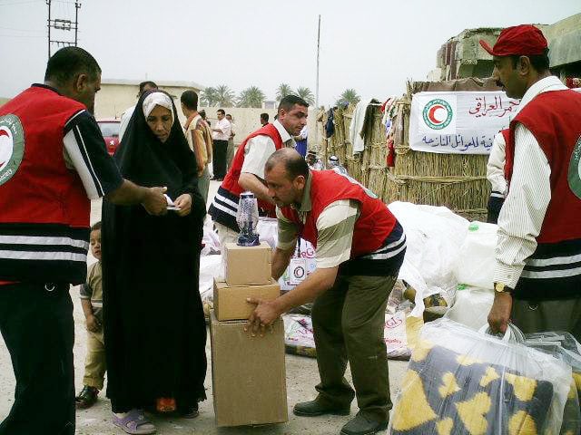 Iraqi Red Cresent Society staff hand out supplies to displaced families at al-Hashemite compound in Babil Province.