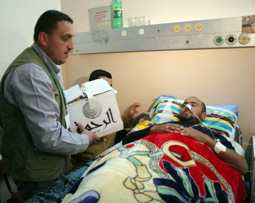 An aid worker from Al-Rahma brings provisions to a patient in a Gaza hospital during an Israeli military offensive in the Strip