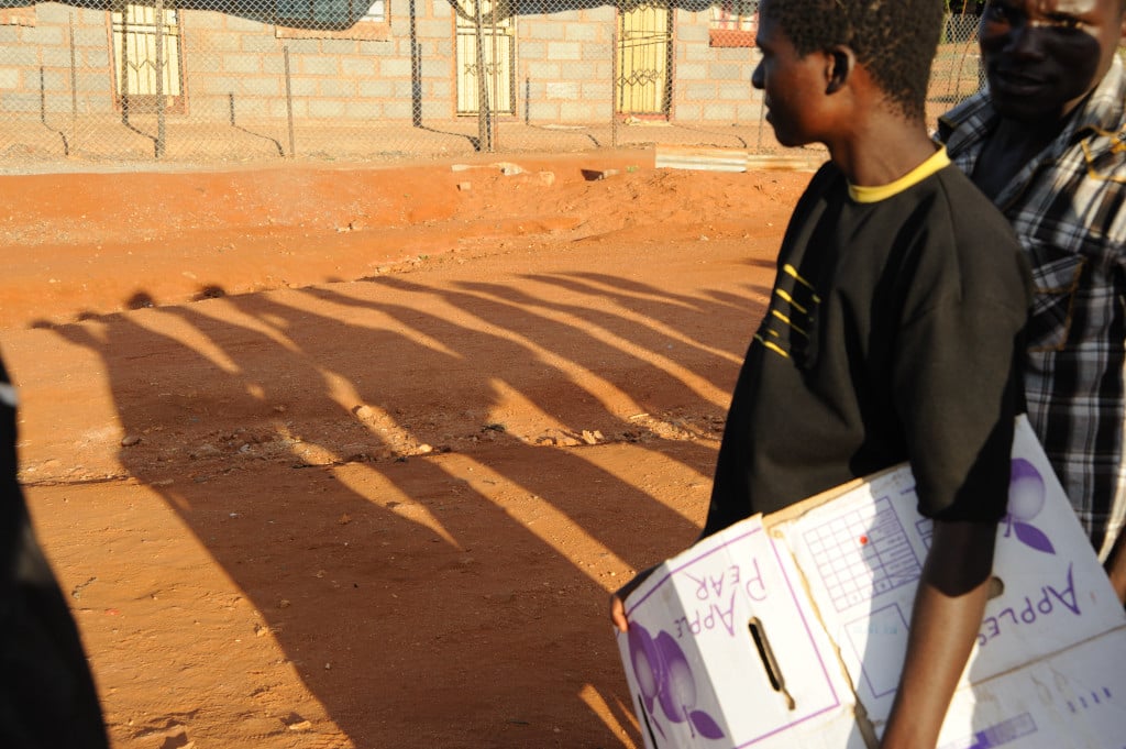 A Zimbabwe asylum seeker queues for registering at a temporary shelter in Musina, carrying cardboard for a bed 