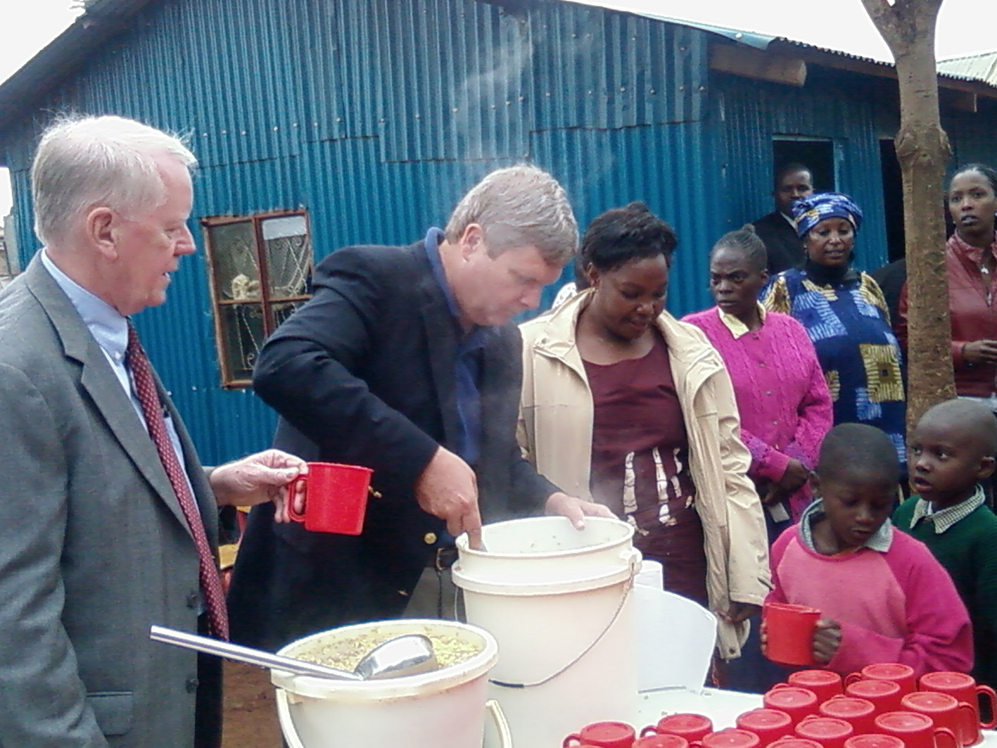 US Secretary of Agriculture Tom Vilocack and US ambassador Micheal Ranneberger feed children in Kibera