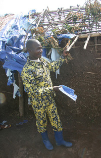 Gaston Mbali demonstrates the fragility of plastic sheeting given to people displaced by the LRA presence in northern Democratic Republic of Congo. Mbali has lived in a rudimentary camp in the town of Niangara since June 2009, when the LRA attacked his vi