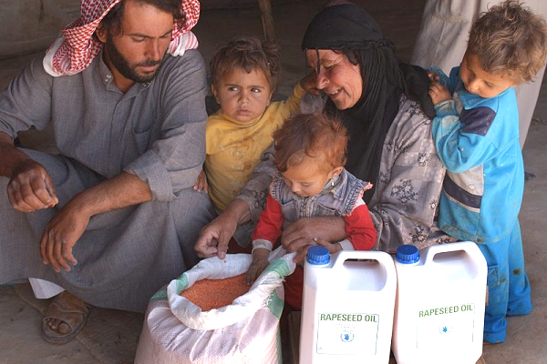 A Syrian family receives food aid at a WFP distribution point (file photo)