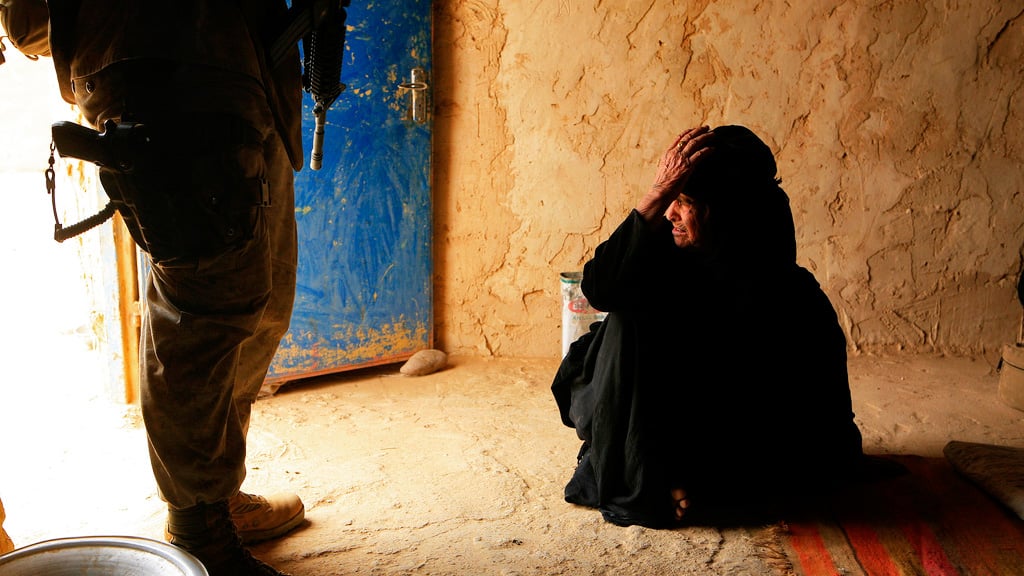 An Iraqi women looks out the door while an U.S. Marine provides security to a U.S. Navy Corpsman in Salah Ad Din, Iraq on May 14, 2008. U.S. Marines and Soldiers are working with Multi-National Forces West (MNF-W) Joint Combat Element in Operation Destroy